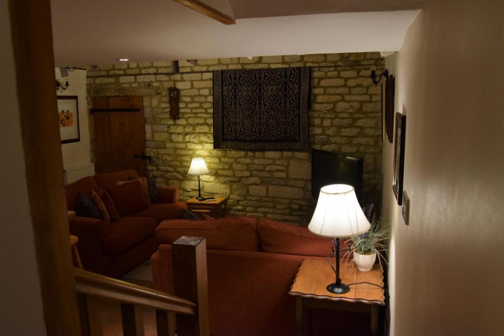 a living room with a couch and a table with a lamp at Swallows' Barn in Corby