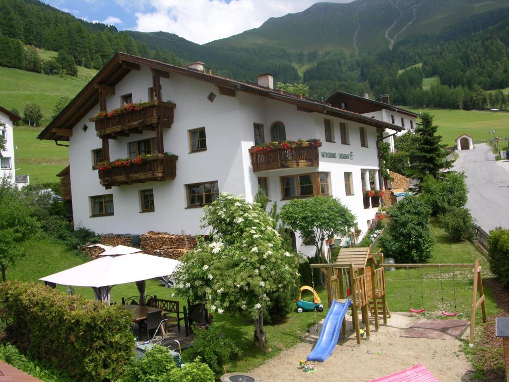 ein großes weißes Gebäude mit einem Spielplatz davor in der Unterkunft Naturerlebnis Lärchenhof in Fendels