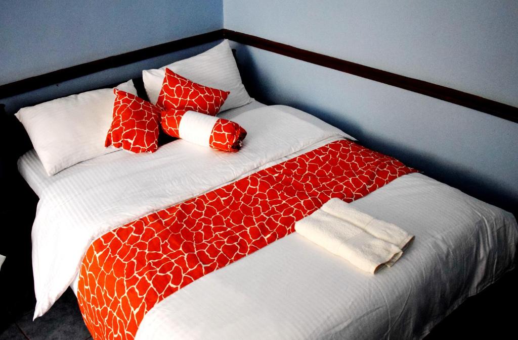 a bed with red and white blankets and pillows at Sheywe Hotel Kakamega in Kakamega