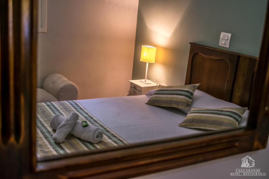 a mirror reflection of a bed in a bedroom at Hotel Casa Grande Itapira in Itapira