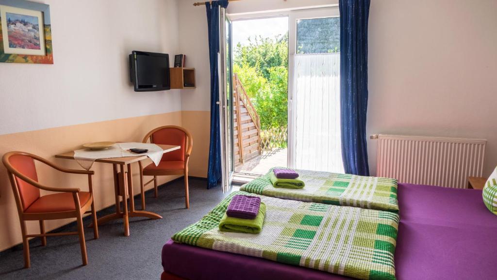 um quarto com uma cama, uma mesa e uma janela em Pension Elmenhorst em Rostock