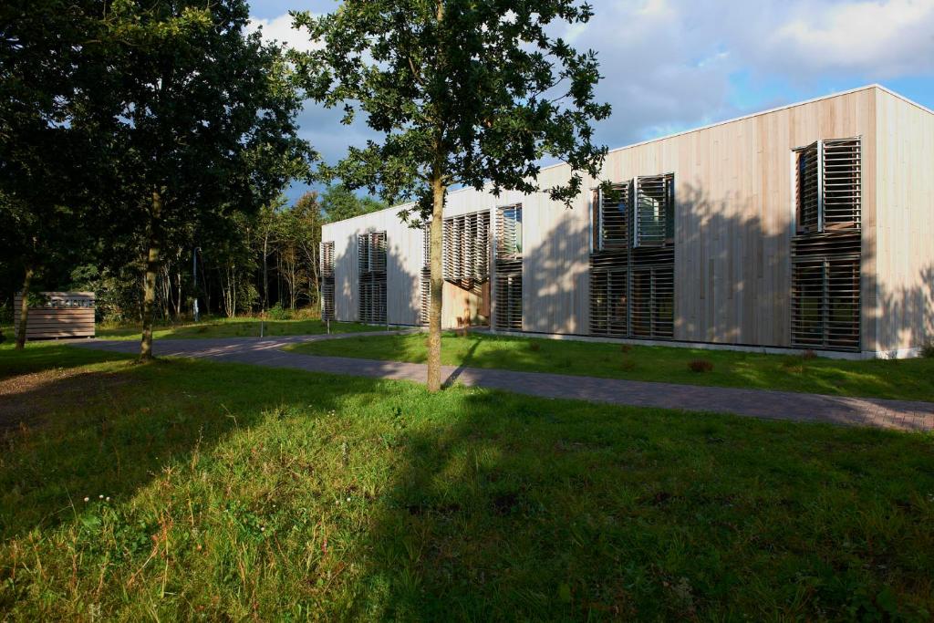 a building in a park with a grass yard at Golf Lodge in Zeijerveen