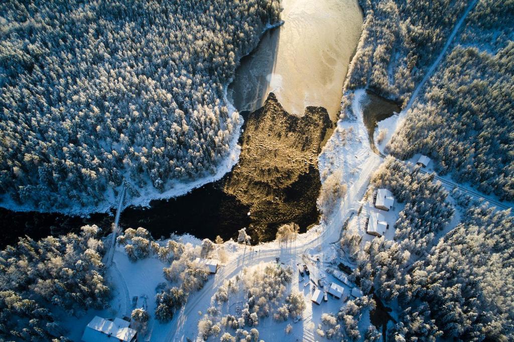 an aerial view of a river with trees and snow at Vaattunki Wilderness Resort in Rovaniemi