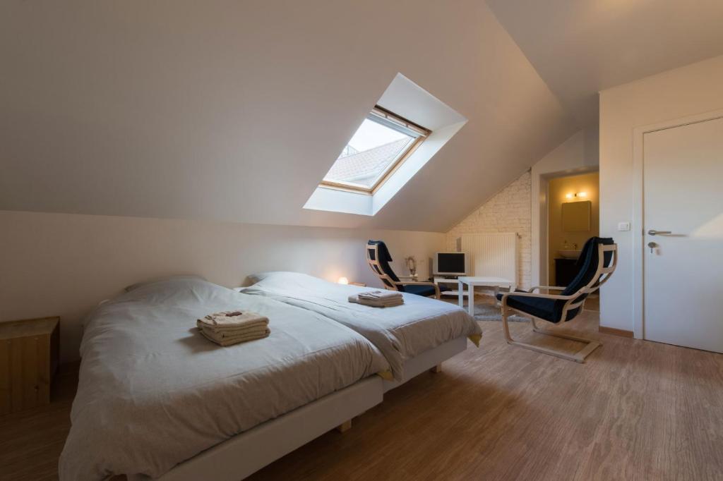 een slaapkamer met een bed en een dakraam bij B&B 't Maanhof in Gingelom