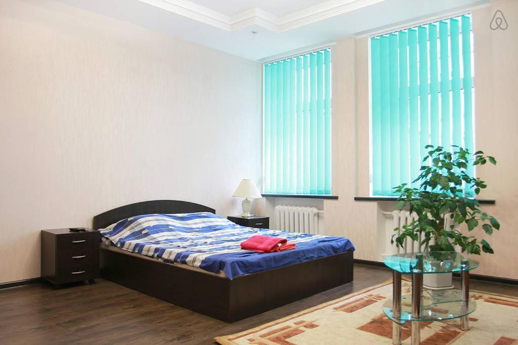 キーウにあるKyivStay Sagaydachnogo Apartmentのベッドルーム1室(ベッド1台、テーブル、植物付)