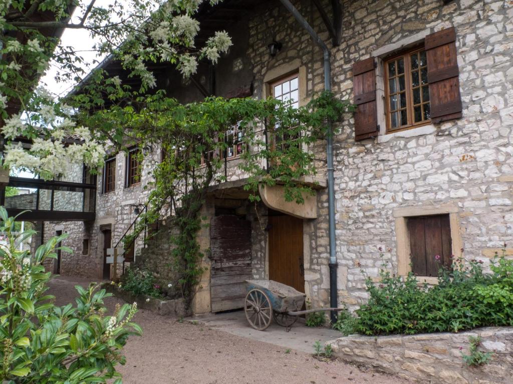 un vecchio edificio in pietra con una porta in legno e un carrello di Logis Hôtel Restaurant La Vieille Ferme, Mâcon Nord a Mâcon
