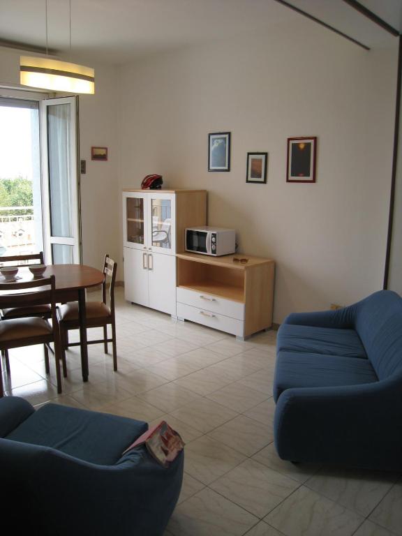 a living room with a blue couch and a table at Strand Lungomare Apartment in Cesenatico