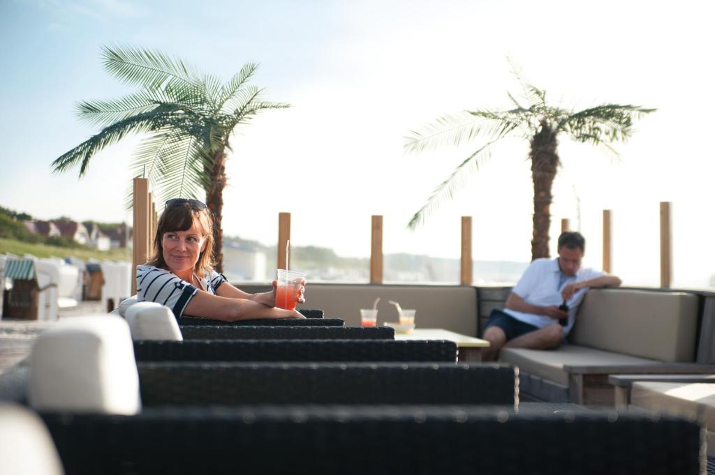 a woman sitting at a table with a drink at Hotel Neptun in Warnemünde