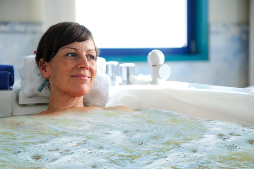 a woman is sitting in a bath tub at Hotel Neptun in Warnemünde