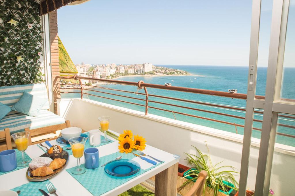 Un balcón con una mesa con comida y vistas al océano. en Marlicante, en Alicante