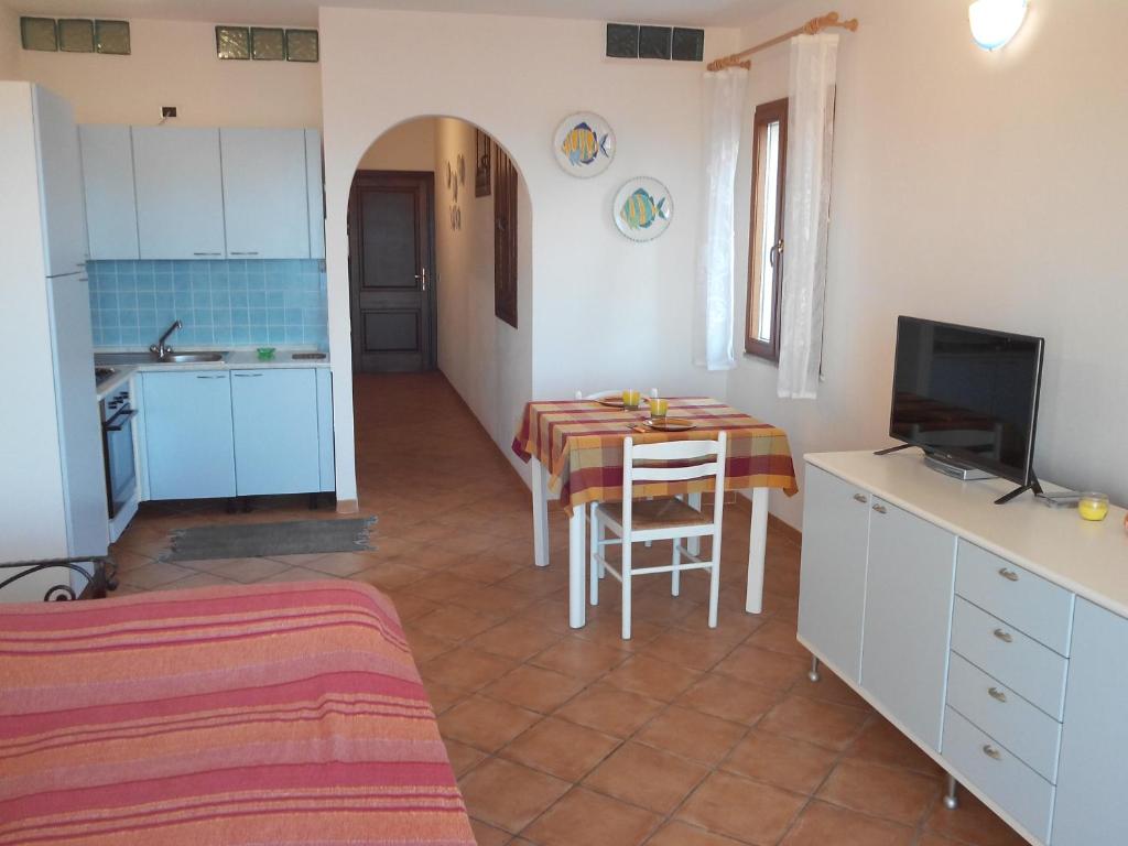 kuchnia i jadalnia ze stołem i telewizorem w obiekcie Splendido mono vista mare con wi fi a 100 mt da spiaggia w mieście Santa Teresa Gallura