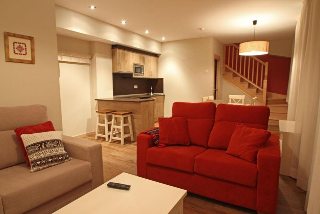 sala de estar con sofá rojo y cocina en Aparthotel Foratata, en Sallent de Gállego