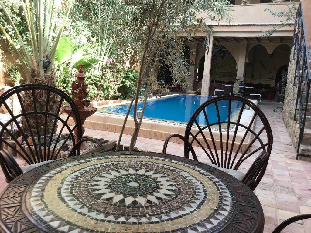 mesa y sillas con mesa y piscina en Dar Amazir, en Agdz