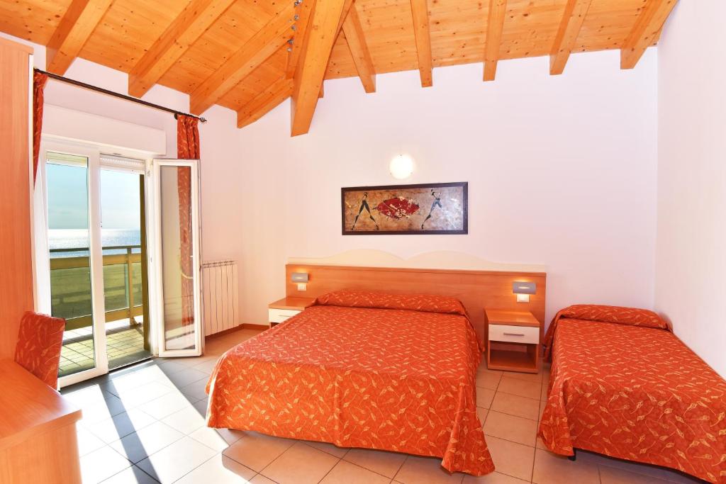 a bedroom with two beds and a balcony at Hotel Villa Olga in Caorle