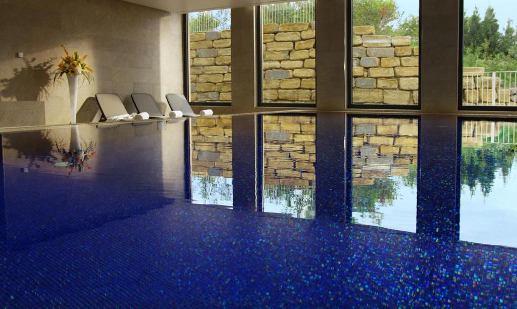 a house with a swimming pool with blue floors and windows at Hotel Cliff Belvedere in Izola