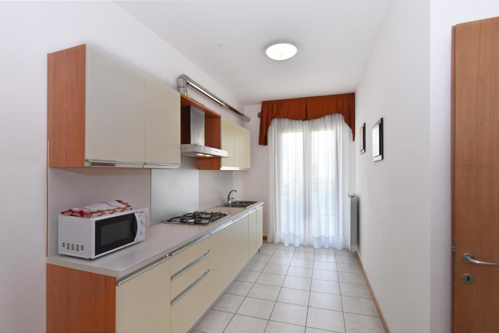 a small kitchen with white cabinets and a microwave at Hotel Villa Olga in Caorle