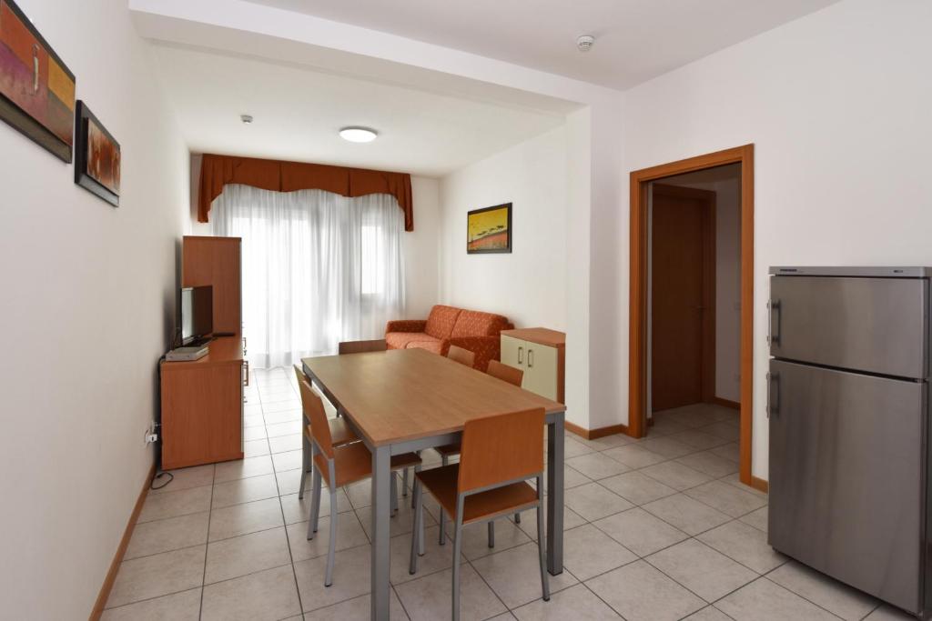 a kitchen and living room with a table and a refrigerator at Hotel Villa Olga in Caorle