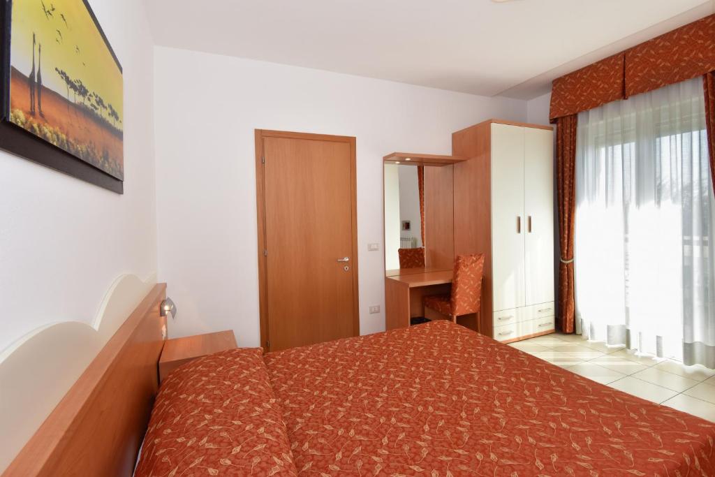 a bedroom with a bed and a desk in it at Hotel Villa Olga in Caorle