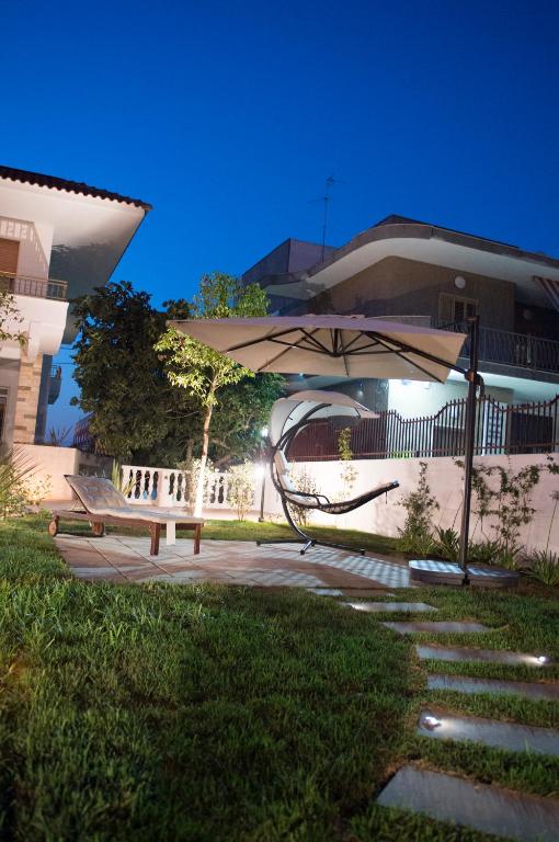 ławka w parku z parasolem przed budynkiem w obiekcie Villa Cristina B&b Alezio w mieście Alezio