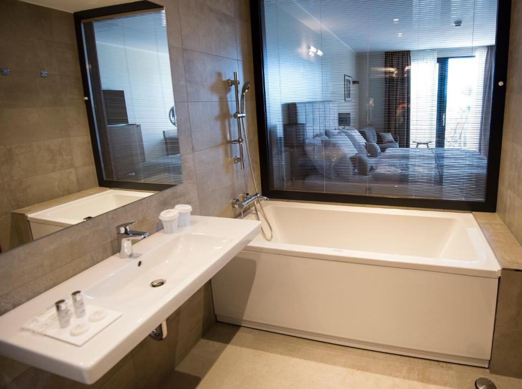 a bathroom with a sink and a bath tub and a window at Hotel Cliff Belvedere in Izola