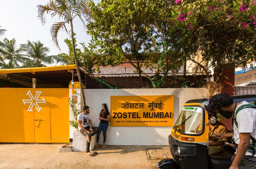 un grupo de personas de pie junto a un edificio amarillo en Zostel Mumbai en Bombay