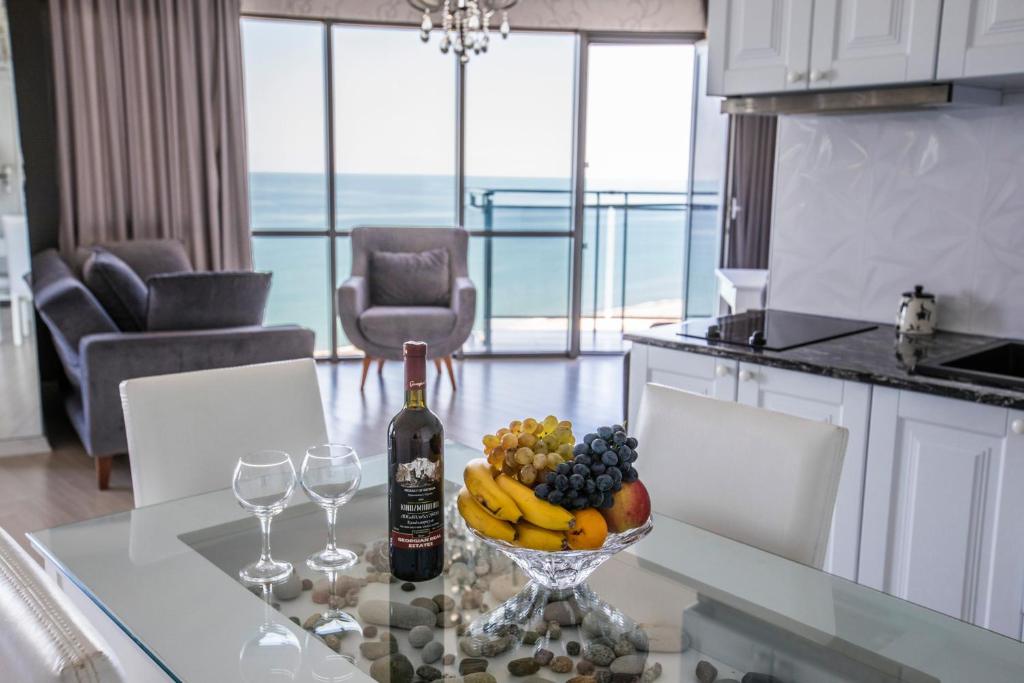 a bottle of wine and a bowl of fruit on a table at Tina's Apartments with Panoramic Sea view in Batumi