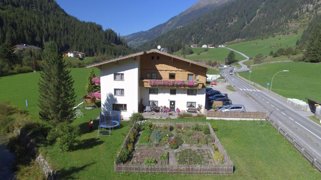 a house on a hill with a garden next to a road at Apartments Seerhof in Kaunertal