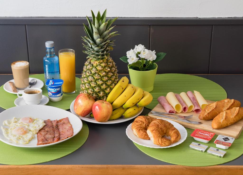 una mesa con platos de desayuno y una piña en Hostal Oliveta, en Barcelona