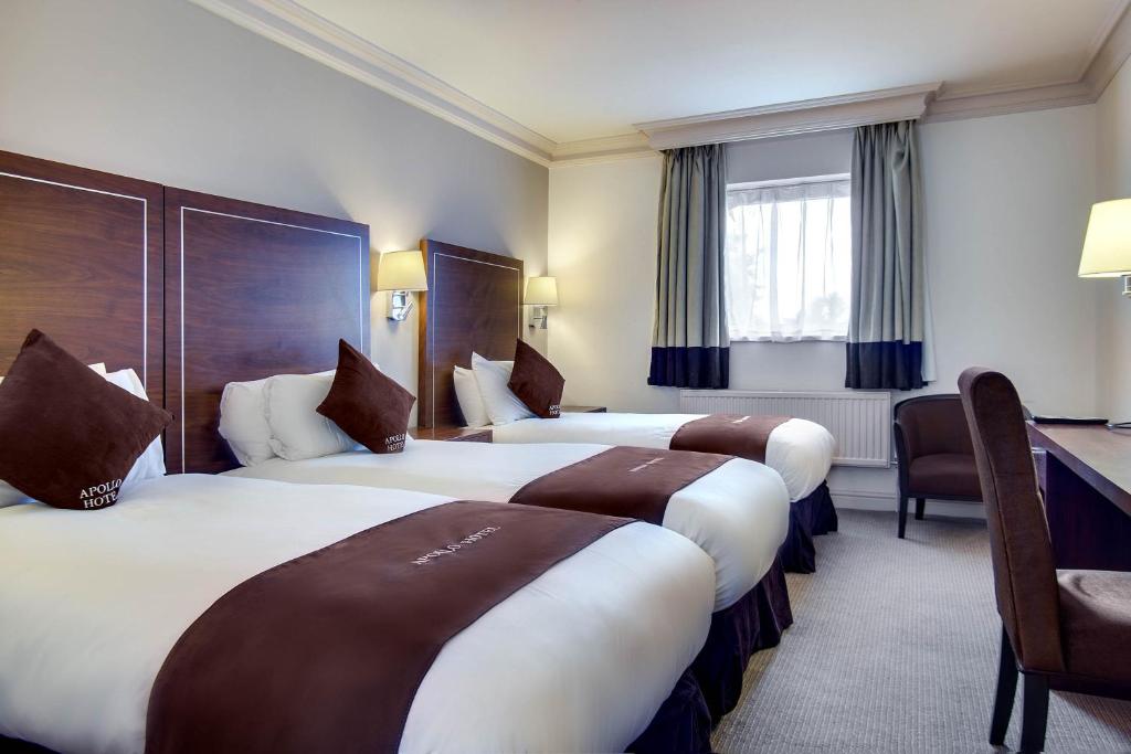 a hotel room with three beds and a desk at Apollo Hotel in Birmingham