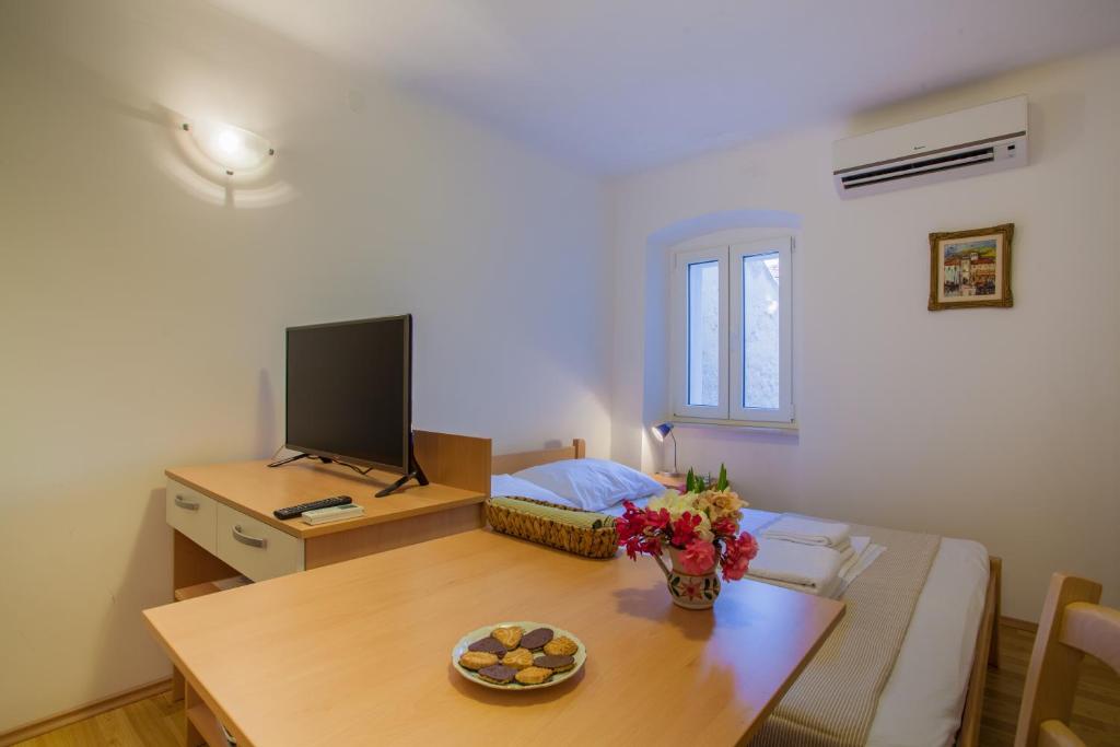 una pequeña sala de estar con mesa y TV en Apartments Calma, en Cres