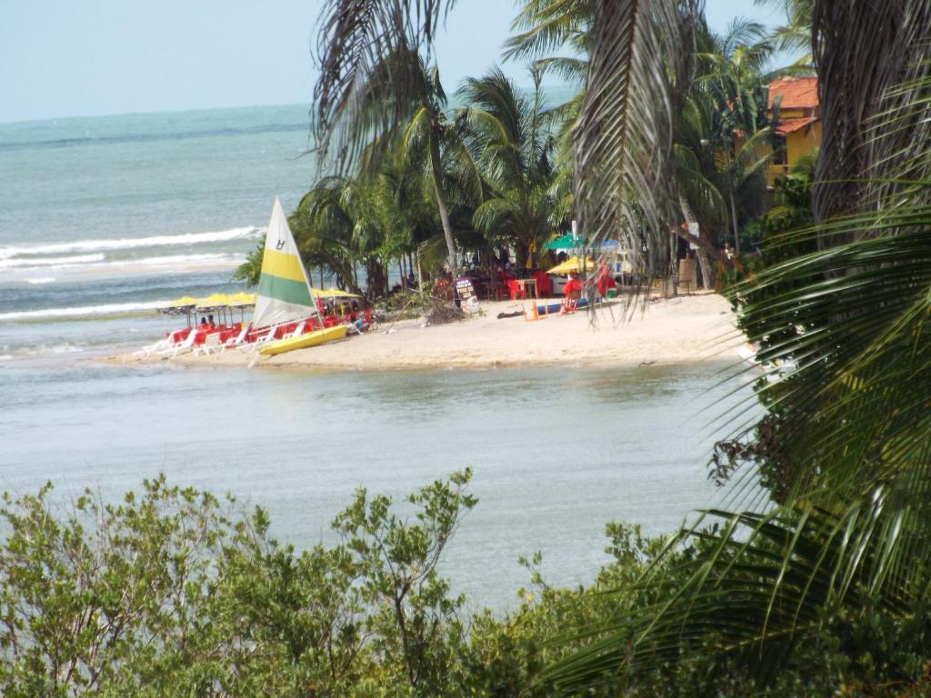 a beach with a sail boat in the water at Casa Manhapeba in Ilha de Boipeba