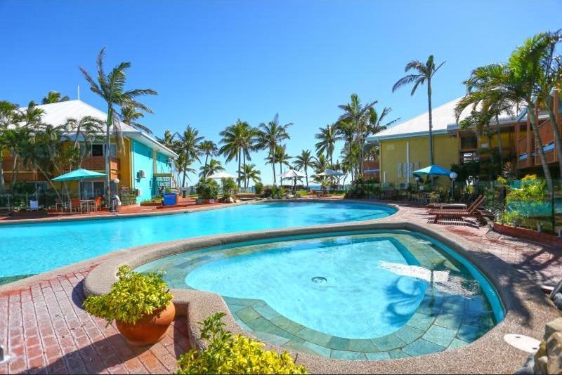 a large swimming pool in a resort with palm trees at WhitsunStays - The Resort by the Sea in Mackay
