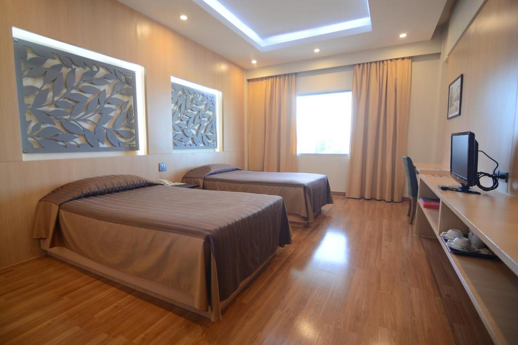 ein Hotelzimmer mit einem Bett und einem TV in der Unterkunft Charoen Hotel in Udon Thani
