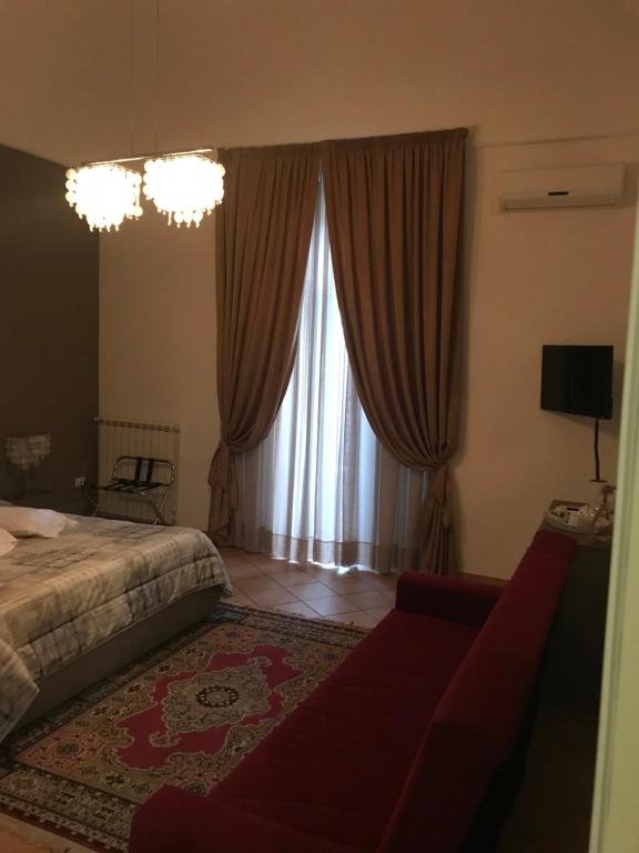 1 dormitorio con cama, sofá y ventana en Mà Maison, en Caserta