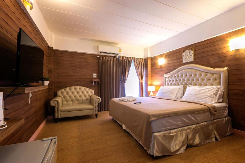 um quarto de hotel com uma cama grande e uma cadeira em Sudyod Apartment em Banguecoque