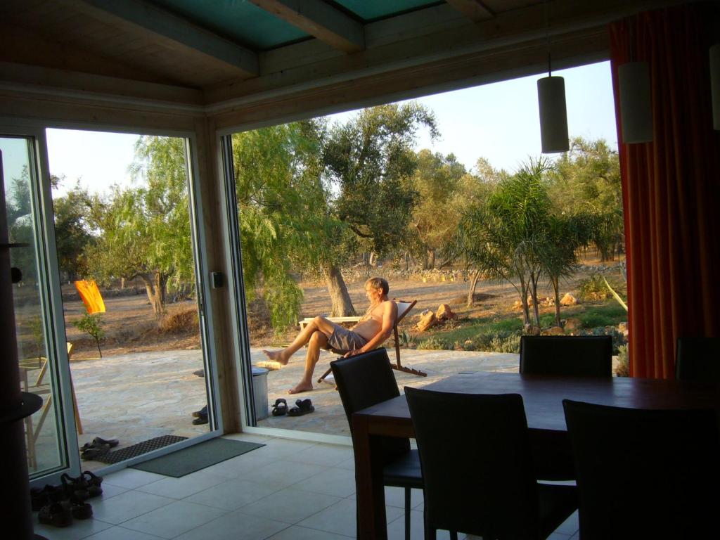 Un uomo seduto su una sedia che guarda fuori da una finestra di casa olivi a Nardò