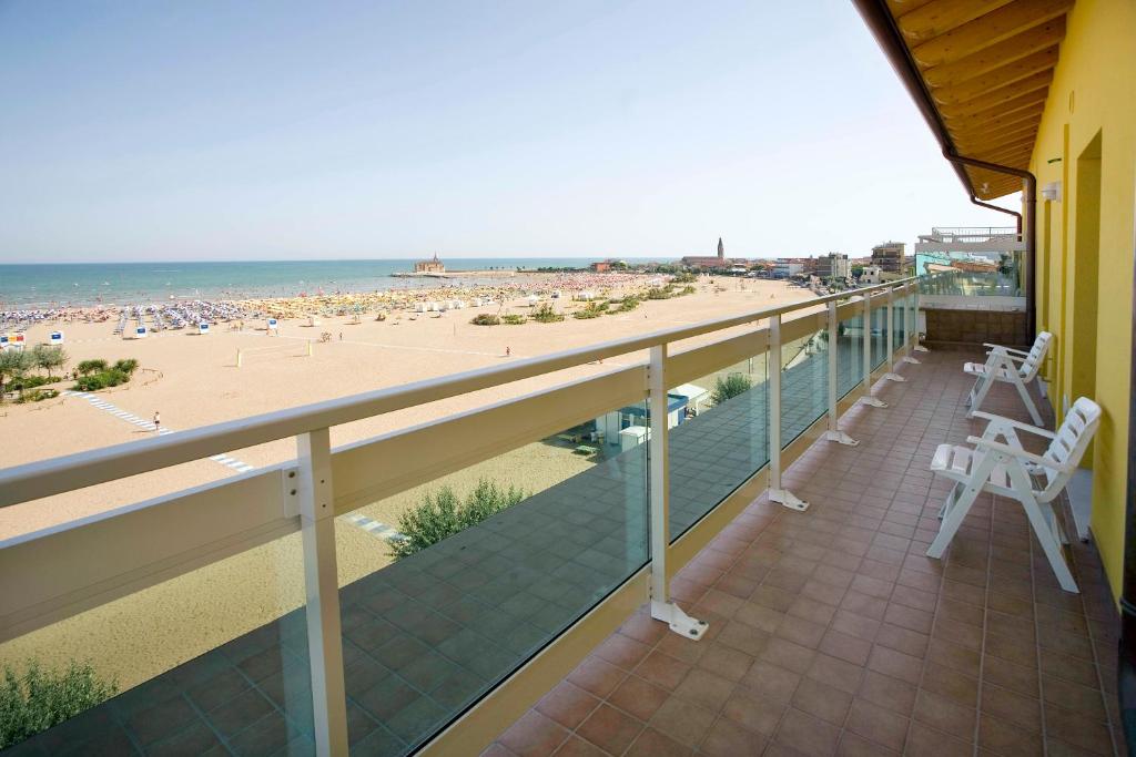 a balcony with two white chairs and a beach at Hotel Villa Olga in Caorle