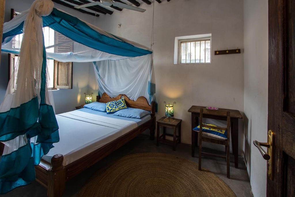 a bedroom with a canopy bed and a table at Kiponda B&B in Zanzibar City