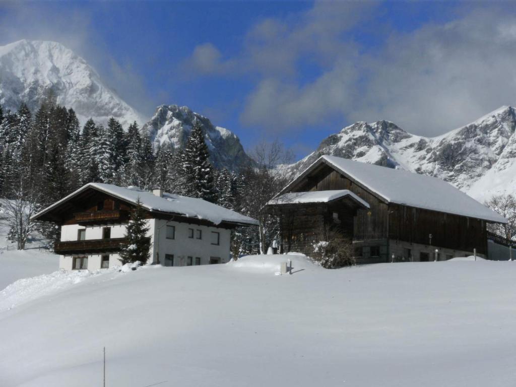a couple of buildings in the snow with mountains at Oberharreithhof in Sankt Martin am Tennengebirge