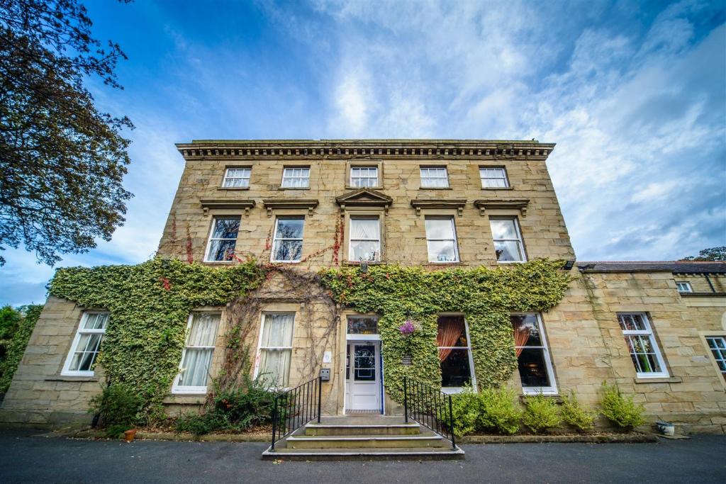 an old brick building with ivy on it at Healds Hall Hotel in Cleckheaton