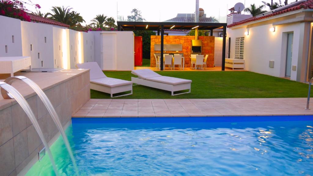 um quintal com uma piscina e cadeiras e uma casa em Villa Calma Luxury Villa em Maspalomas