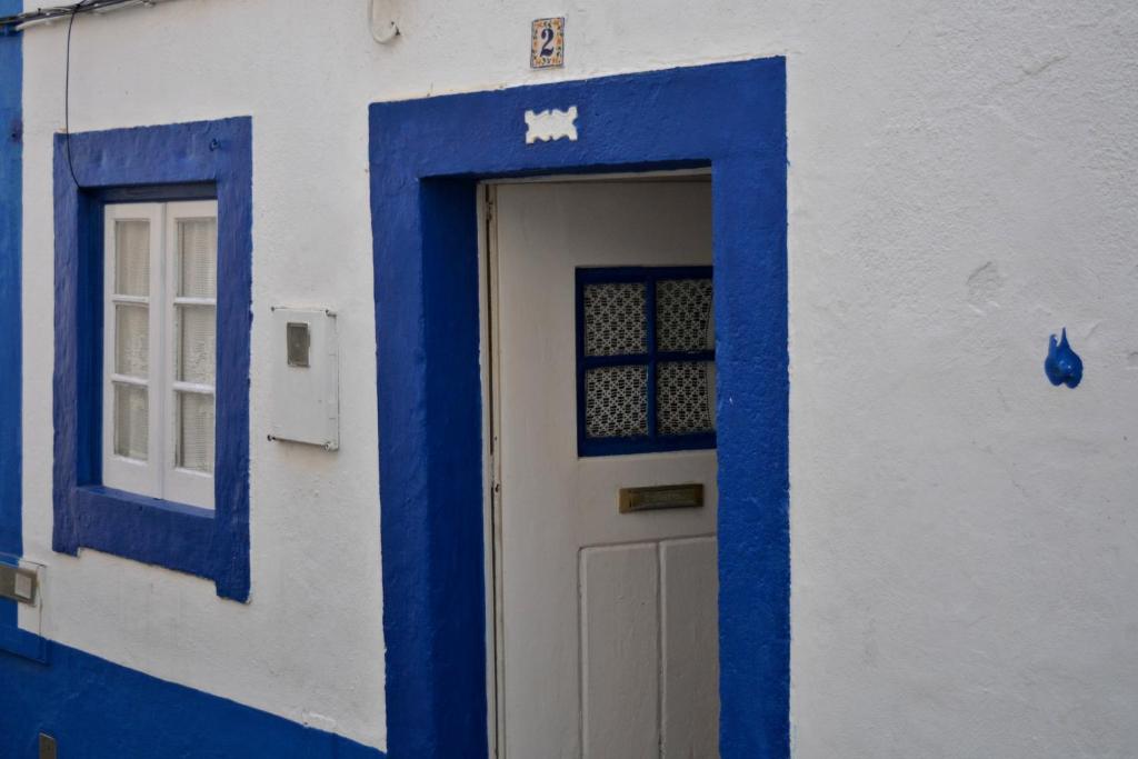 ein blau-weißes Gebäude mit einer Tür und einem Fenster in der Unterkunft Casa Ericeira in Ericeira