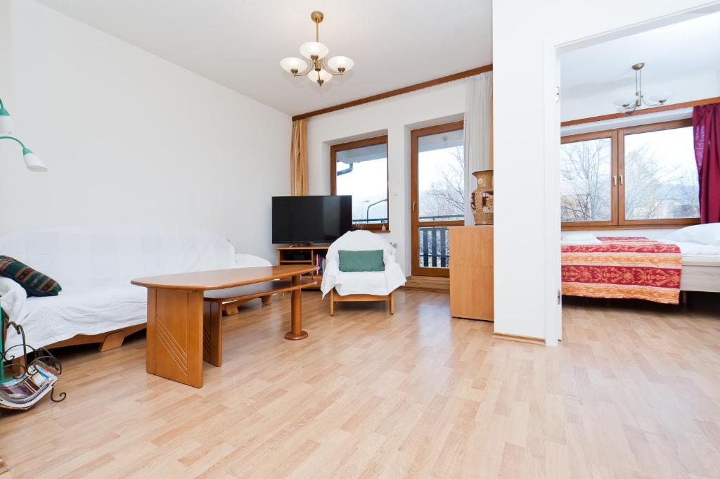 a room with two beds and a desk with a television at Apartamenty Sun & Snow Centrum in Zakopane