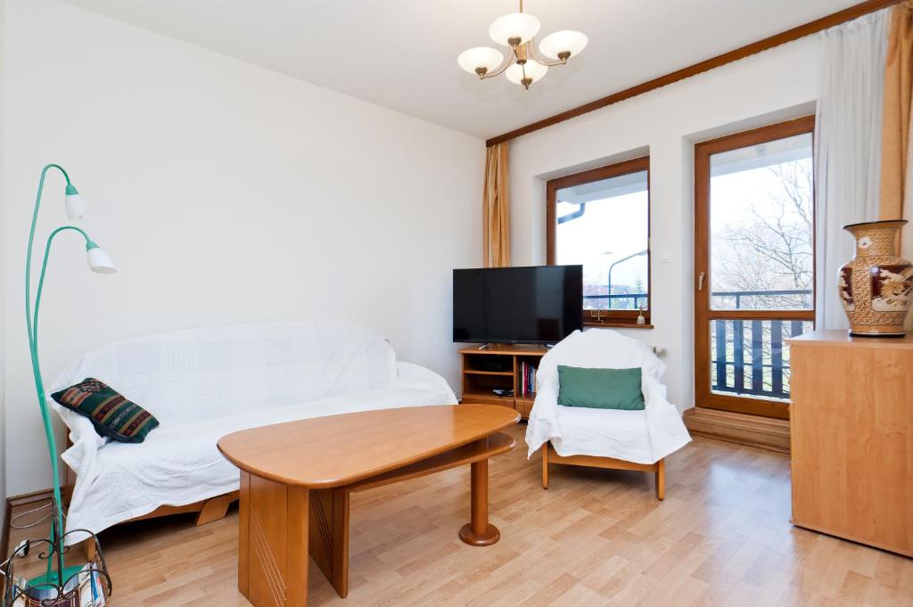 a bedroom with a bed and a table and a tv at Apartamenty Sun & Snow Centrum in Zakopane
