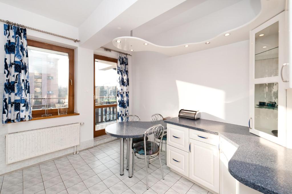 a kitchen with white cabinets and a table with chairs at Apartamenty Sun & Snow Centrum in Zakopane