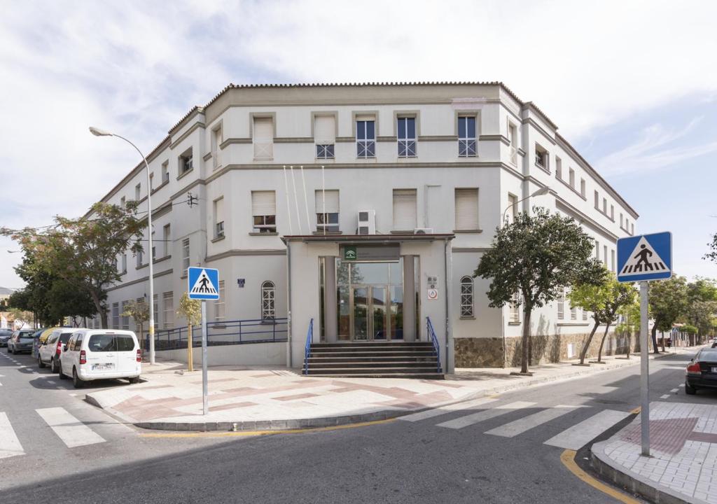 un edificio blanco en una calle con coches aparcados delante en Albergue Inturjoven Malaga, en Málaga