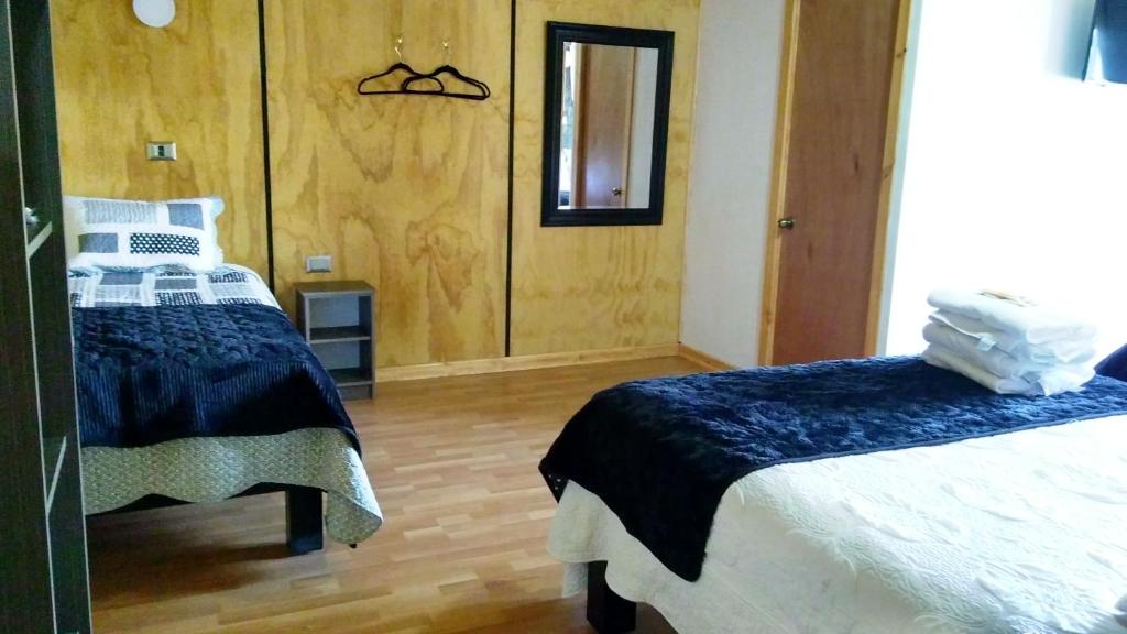 a bedroom with two beds and a mirror at Residencial del Maule in Linares