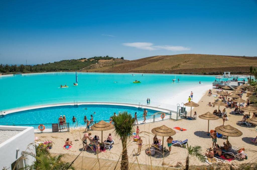 エステポナにあるAlcazaba Lagoon Estepona Golfの青い水のビーチの人々とプール