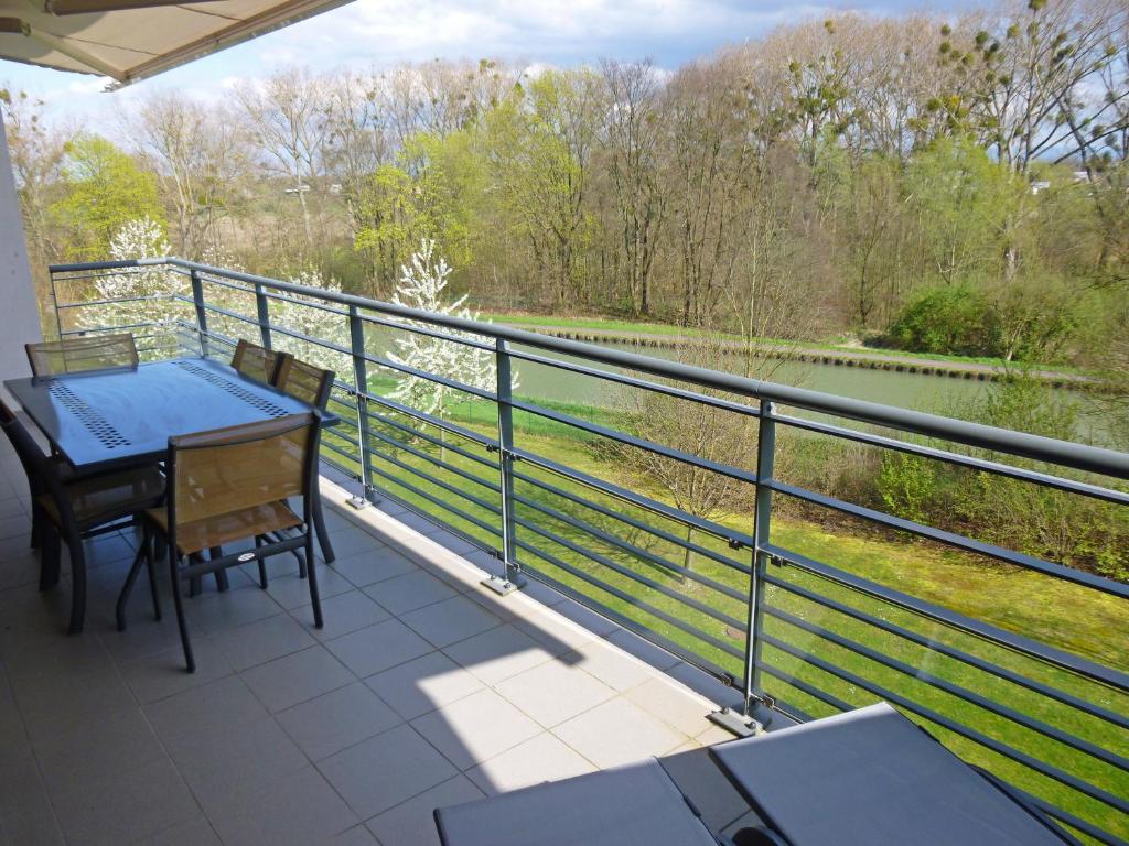 a balcony with a table and chairs and a view of a river at Beau Rivage Appart' in Souffelweyersheim