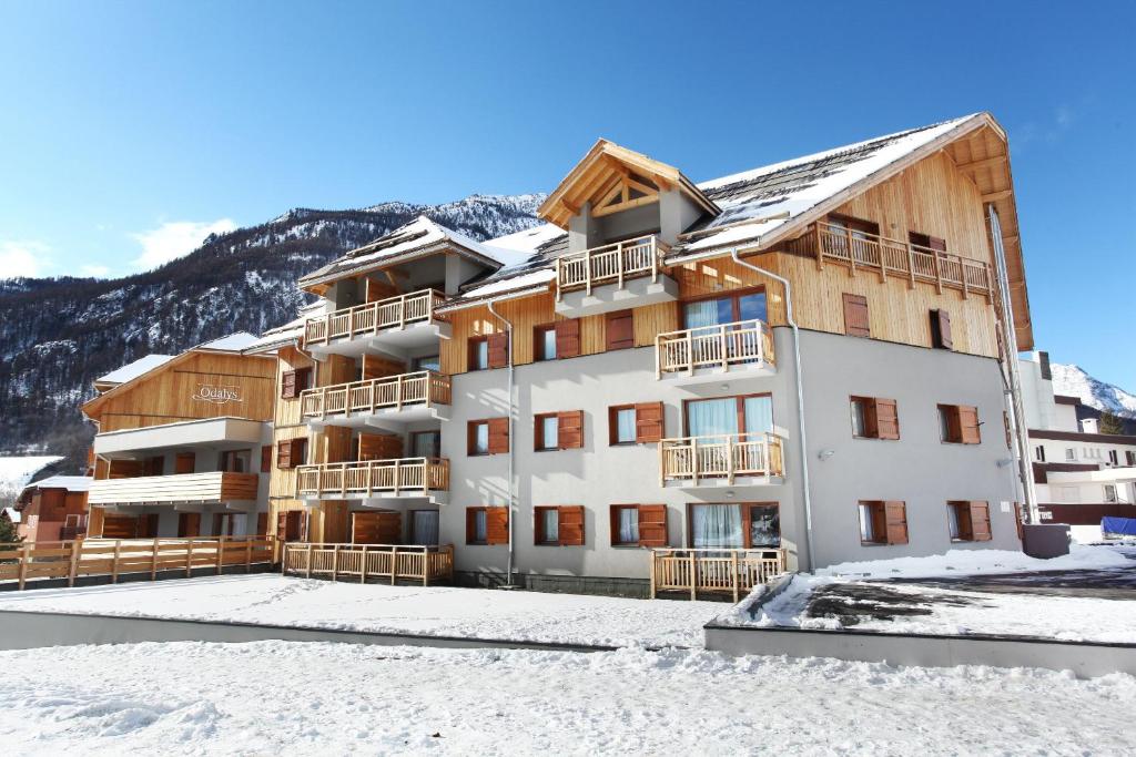 a building with snow in front of it at Résidence Odalys Aquisana in La Salle Les Alpes